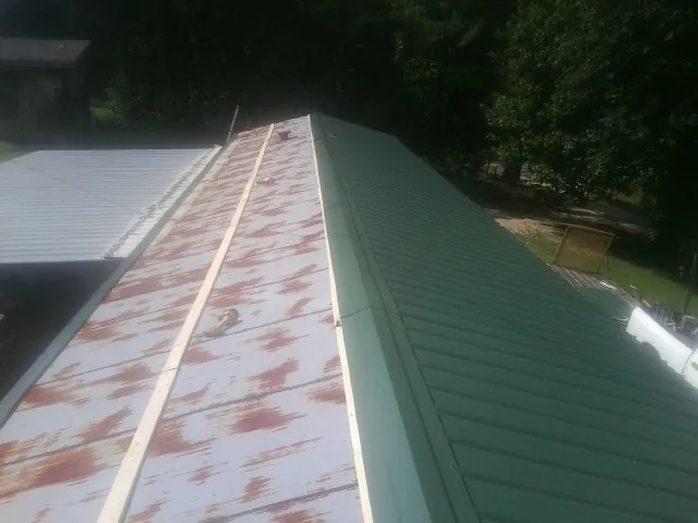Old rusted panels beside newly installed green metal roofing — Wind Damage Roof Repair by Roofing Brothers in Lisle