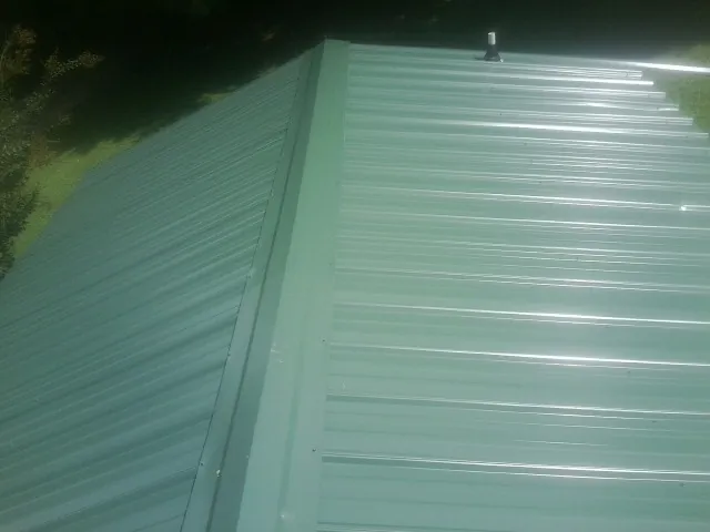 New green metal panels meeting at the ridge of a roof — Flat Roof Repair work by our crew in Lisle