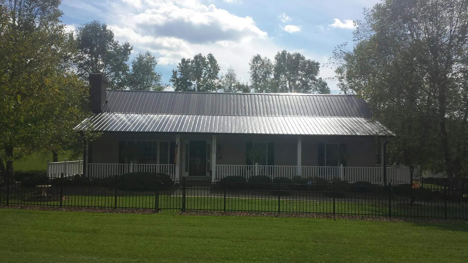 Gray metal roof on a brick ranch with a full width front porch — Gutter Guard Installation work by our crew in Lisle