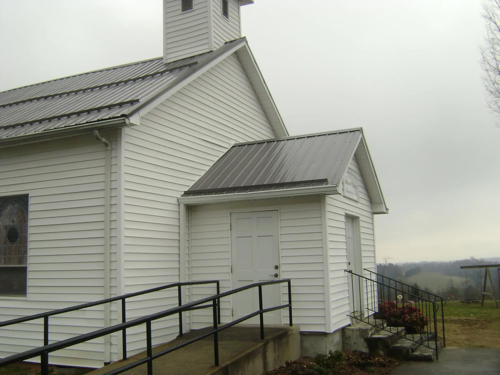 Gray metal roof on a white clapboard church with a steeple in Lisle