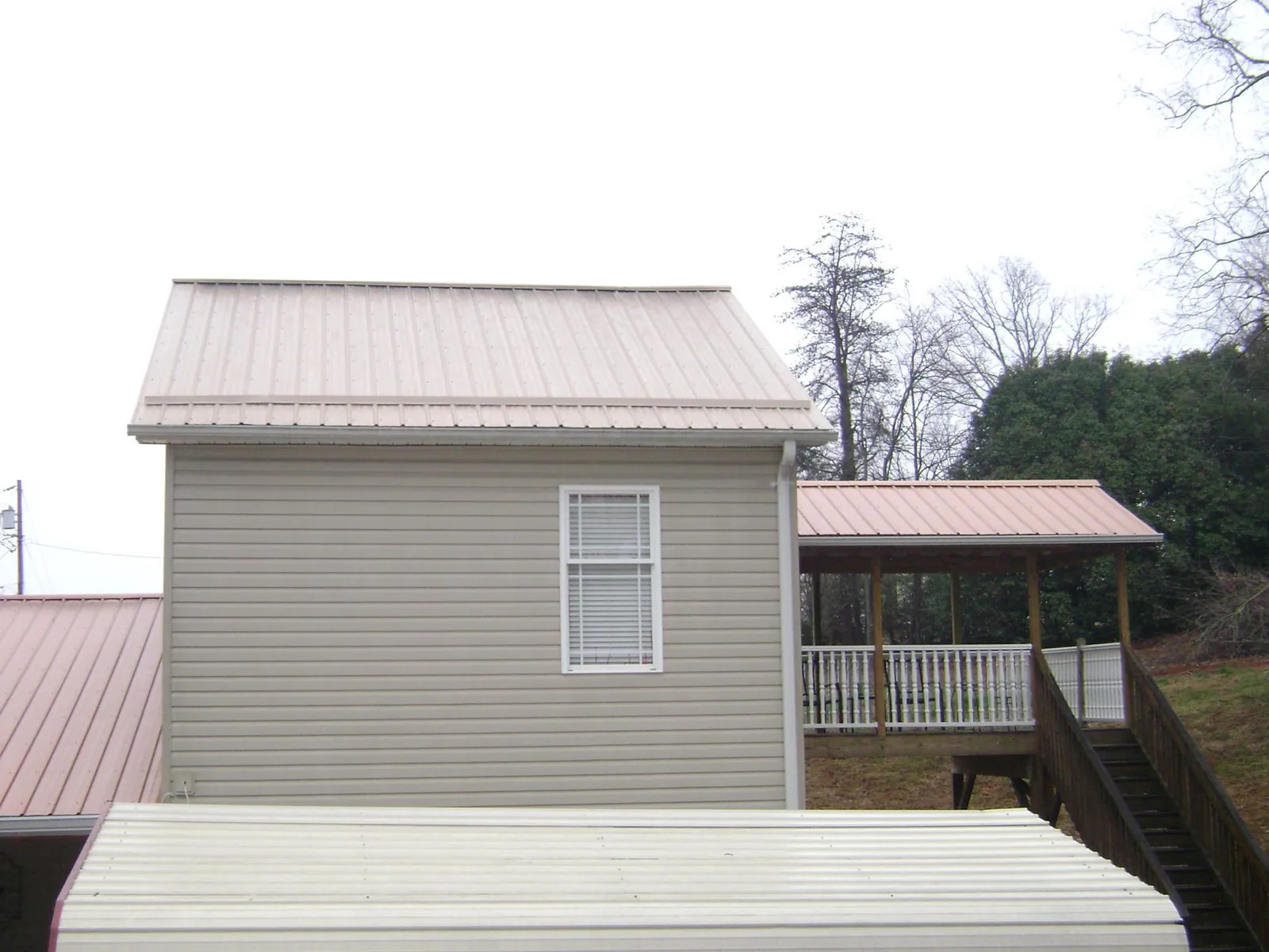 Tan metal roofs on a two story addition and attached porch, from a Roof Replacement job in Lisle